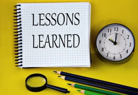 LESSONS LEARNED - words in a white notebook with an alarm clock, pencils an.. Stock Photos