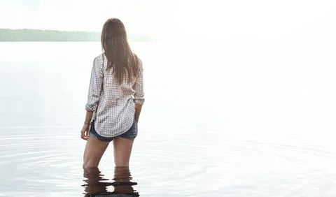 Let your spirit sway gently with the waters. Rearview shot of a young woman Stock Photos