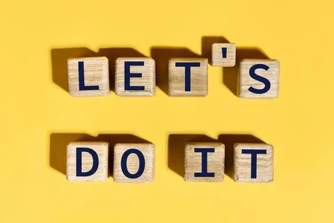 Let's do it motivation phrase on wooden blocks over yellow background Stock Photos
