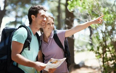 Lets explore that trail. A happy young couple backpacking through the woods. Fotos Stock