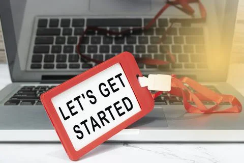 Let's get started text written on red name tag placed on a laptop. Stock Photos