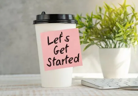 Let's Get Started Text Written on Sticky Paper on Coffee Gass on Office Desk. Stock Photos
