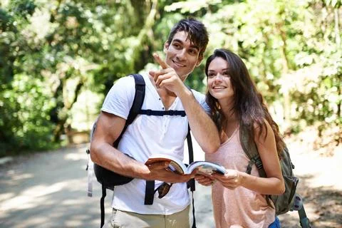 Lets go explore that way. a young couple looking at a guidebook while out hiking Fotos de archivo