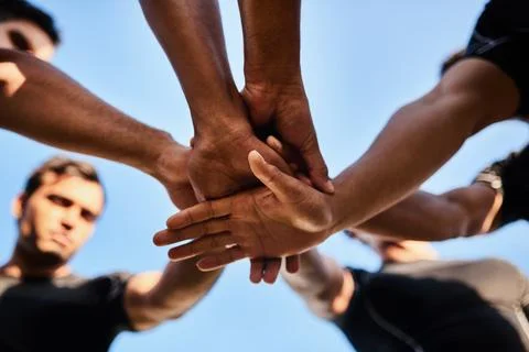 Lets go team. a handsome group of sportsmen huddled together with their hands in Stock Photos