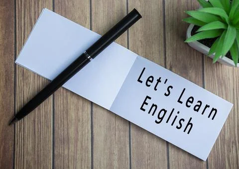 Lets learn english text on notepad with potted plant on a wooden desk 库存照片