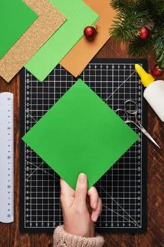 Let's make a simple paper craft. A Christmas tree bookmark. A hand holding a  Stock Photos