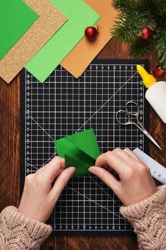 Let's make a simple paper craft. A Christmas tree bookmark. Hands fold the .. Stock Photos