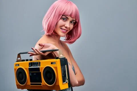 Let's make some noise. Young woman in a pink wig holding yellow record-played Stock Photos