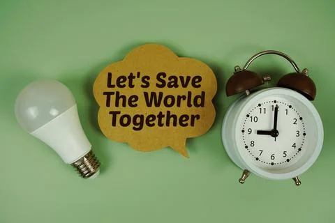 Let's Save The World Together text with light bulb and alarm clock on green.. Stock Photos