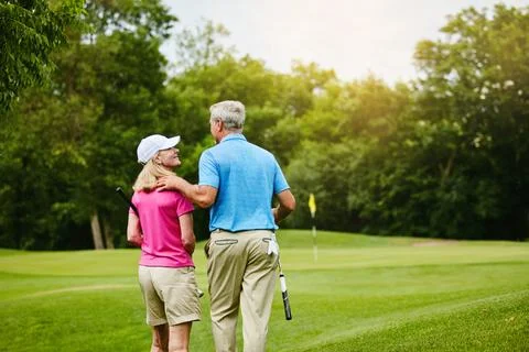 Lets take a romantic walk towards our course. a mature couple on a golf course. Fotos de archivo
