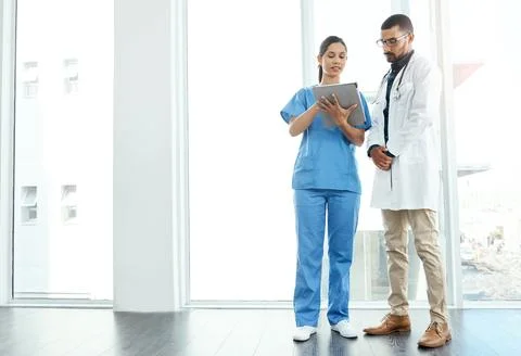 Lets talk about our next move. two young doctors using a digital tablet in a Stock Photos