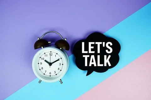 Let's Talk text on speech bubble with alarm clock top view on blue, purple .. Stock Photos