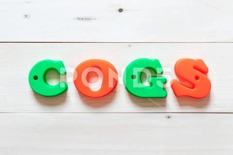 Letter block in word COGS (Abbreviation of Cost of goods sold) on white wood Stock Photos