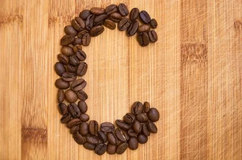 Letter C, alphabet from coffee beans. isolated on wood Stock Photos