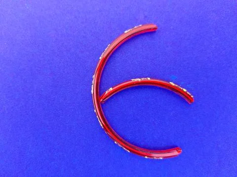 Letter E made of glass bangle isolated on blue background Stock Photos