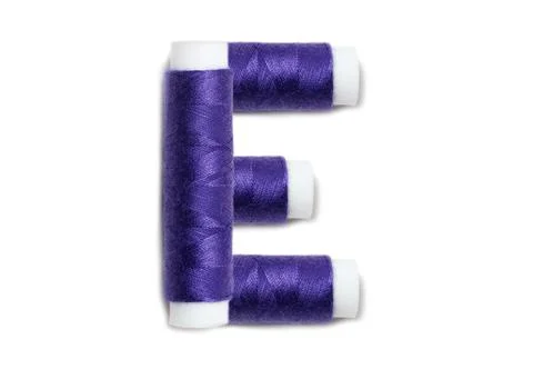 Letter of E from thread spools, isolated on white background. Alphabet concep Stock Photos