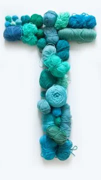 The letter T is made of multi-colored skeins and a ball of yarn. White Stock Photos