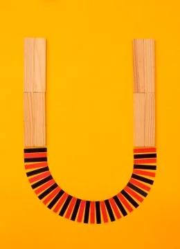 Letter "U" formed of building bricks and red and black paper stripes at yellow Fotos de archivo