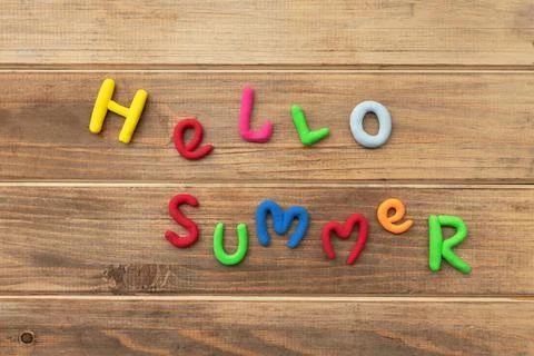Letters made of multi-colored plasticine hello summer on old brown wooden tab Stock Photos