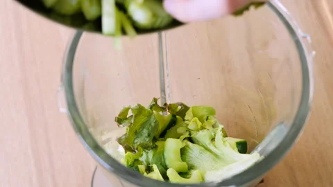 Lettuce, cucumber, green celery are added to the mixer to make a wellness Stock Footage 178484730
