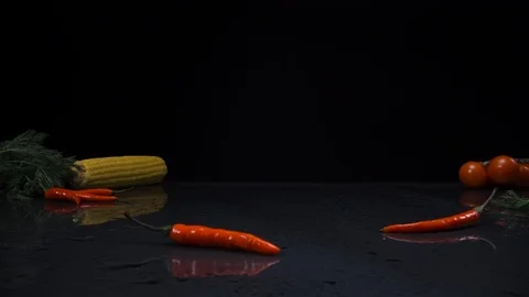 Lettuce leaves fall on a table on a black background surrounded by vegetables. Video stock 125476602