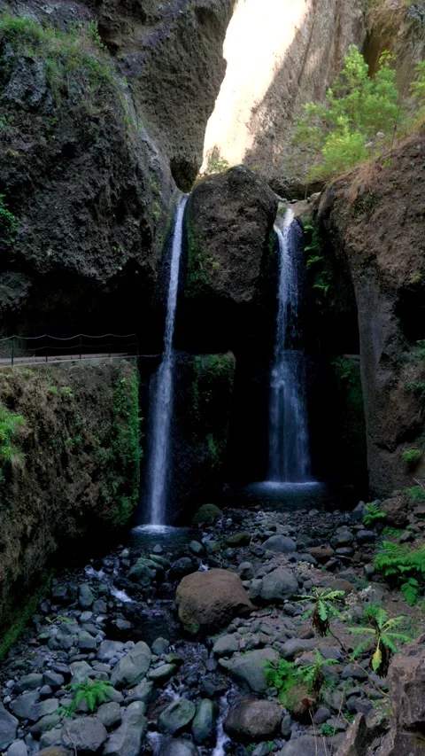 Levada Nova waterfall nestled in the verdant hills of Lombada da Ponta do Sol Stock Footage 345636542