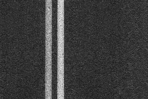 Level asphalted road with a dividing stripes. The texture of the tarmac. Stock Photos