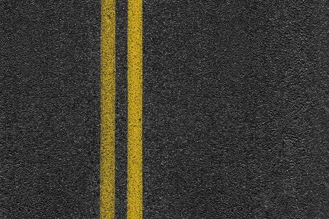 Level asphalted road with a dividing stripes. The texture of the tarmac. Stock Photos
