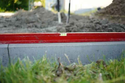 Level on the concrete kerb. Leveling on the construction site. Work zone. Stock Photos