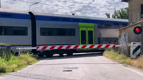 Level crossing closed and red light,double-decker train crossing Stock Footage 277467361