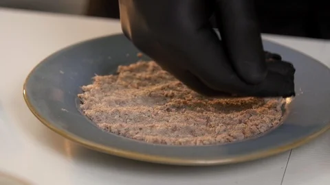 Level out layer of canned fish puff salad cooking in latex gloves Stockbeeldmateriaal 121364368