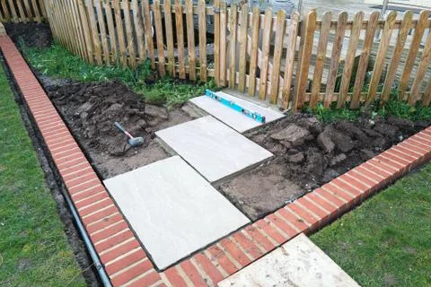 A level tool being used to install a new paving stones to a picket fence Stock Photos