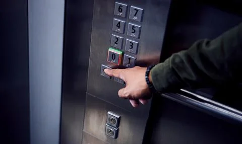 Level up. an unrecognizable man pressing a button in an elevator. Fotos de archivo