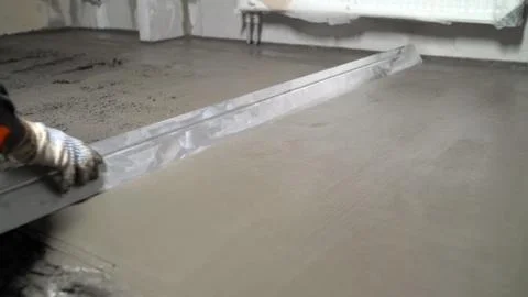 Leveling the floor of a large construction spatula. The worker pours the floo Stock Photos
