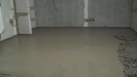 Leveling the floor with a spatula. Builder smoothing wet mortar on the floor. Stock Photos
