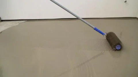 Leveling the floor using spiked roller. Construction worker mixes leveling .. Stock Photos