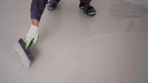 Leveling a liquid floor with a spatula. A worker spreads liquid on the floor  Stock Photos