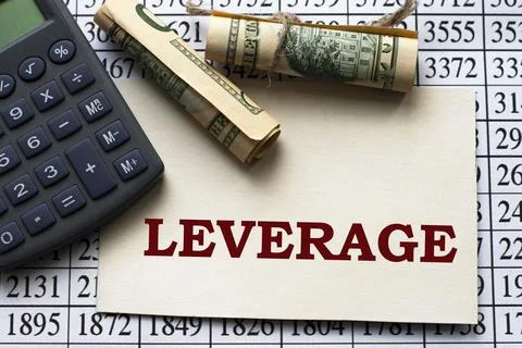 LEVERAGE word on a white sheet against a table with numbers, banknotes and ca Stock Photos