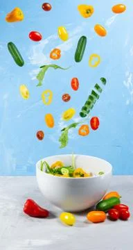 Levitating mixed fresh vegetables on blue background Stock Photos