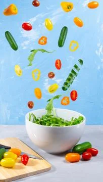 Levitating mixed fresh vegetables on blue background Stock Photos