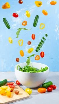 Levitating mixed fresh vegetables on blue background Stock Photos