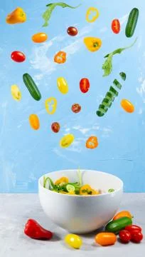 Levitating mixed fresh vegetables on blue background Stock Photos