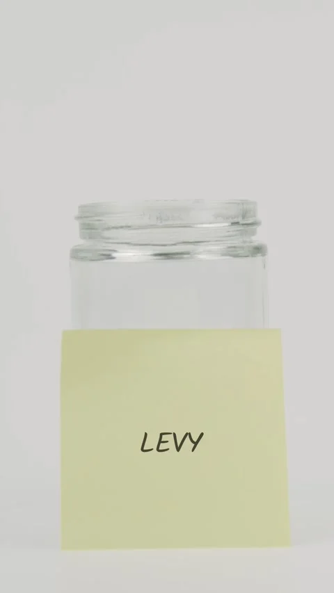 Levy text or word on yellow sticky note attached to glass jar with hand Stock Footage 311749938