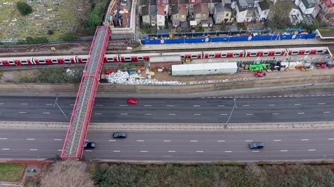 Leyton station top-down drone pan as train departs over A12 in London Vídeo Stock 328938602