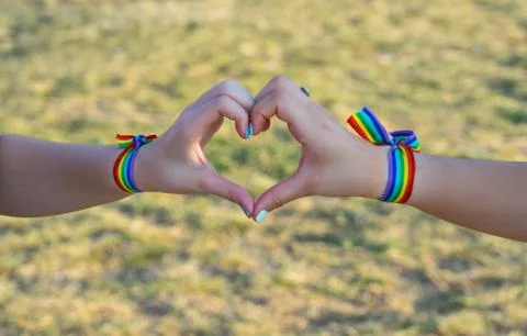 LGBT concept, two hands making a heart shape together with a rainbow flag bra Stock Photos