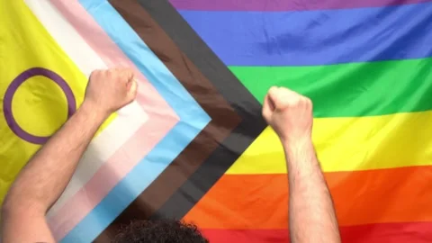 Lgbtq+ pride 2024 protest concept. Male raises fists by new lgbt flag Stock Footage 274500541