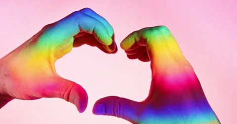 LGBTQ+ Pride Heart Gesture with Two Hands in Rainbow Light over Pink Background Stock Footage 342068716