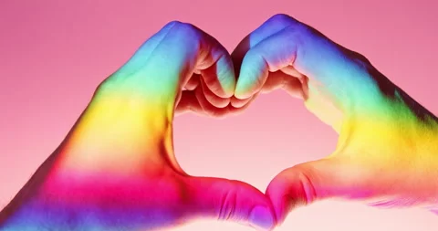 LGBTQ+ Pride Heart Gesture with Two Hands in Rainbow Light over Pink Background Stock Footage 342070529