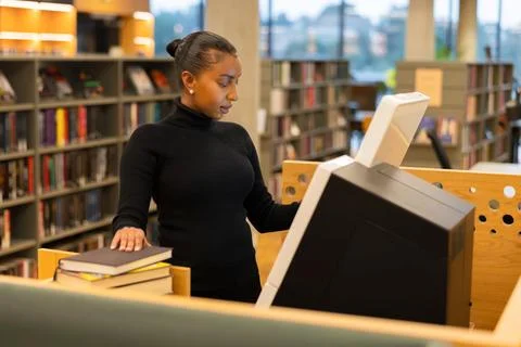 Librarian using self-service terminal in library Stock Photos