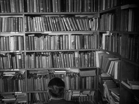 Library room with men picking and reading books, UK, 1940 Stock Footage 130677961